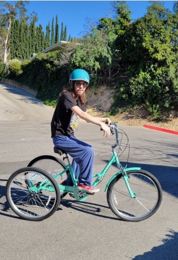 Young adult riding a three-wheeled bike with a helmet.