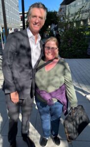 Photo of Michelle standing and smiling with Governor Newsom outdoors.